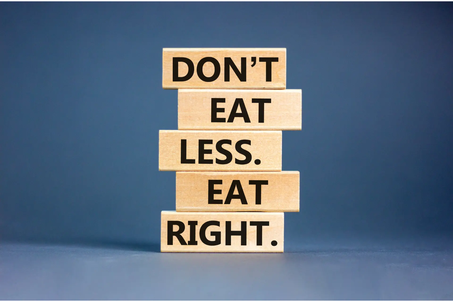 Holzkloetze uebereinandergestapelt, auf jedem ein Wort, Gesamttext: Don't eat less. Eat right., also intuitives Essen lernen