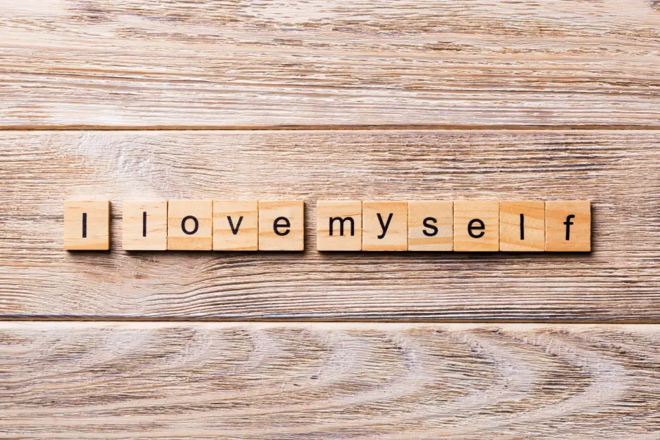 Holzplaettchen mit einzelnen Buchstaben die den Satz I love myself ergeben